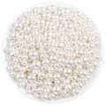 Ivory pearl craft beads in assorted sizes poured into a white bowl, top-down view.