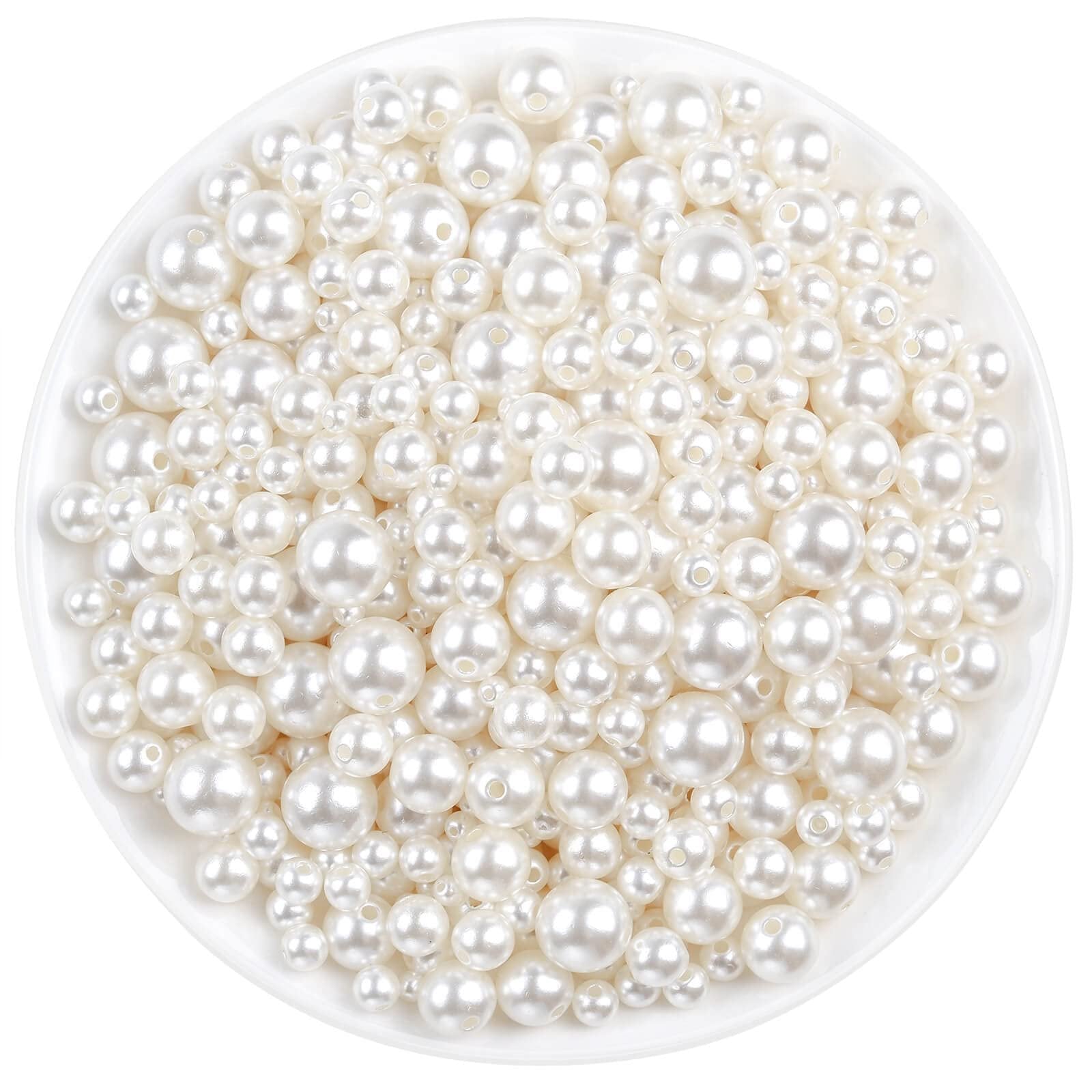 Ivory pearl craft beads in assorted sizes poured into a white bowl, top-down view.