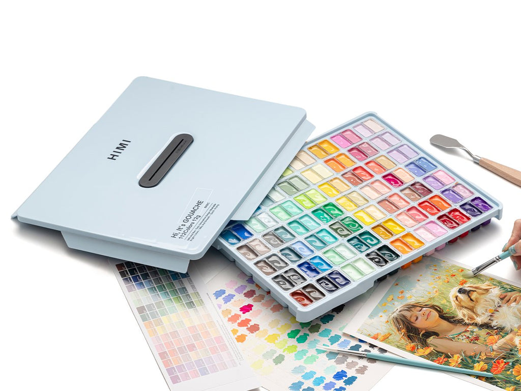 Light blue jelly gouache paint set with 112 colors open, showing paint pans, palette knife, brushes, and artwork of a girl with a dog.