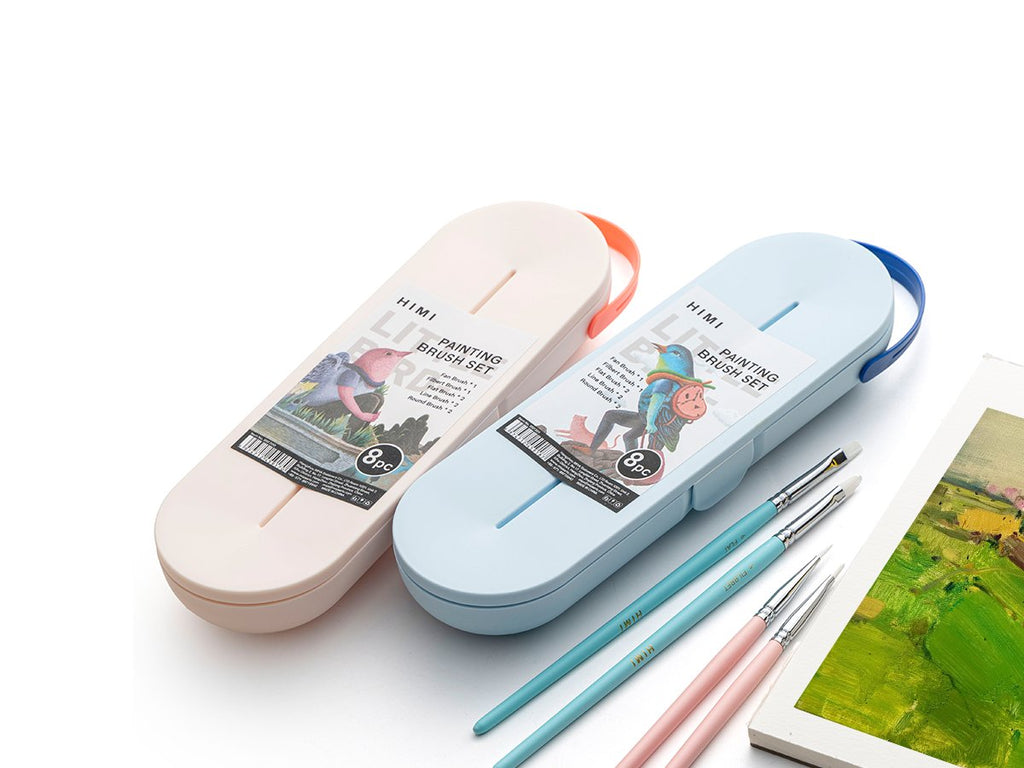 Two portable painting brush sets, one cream and one light blue, with brushes and a painting in the foreground.