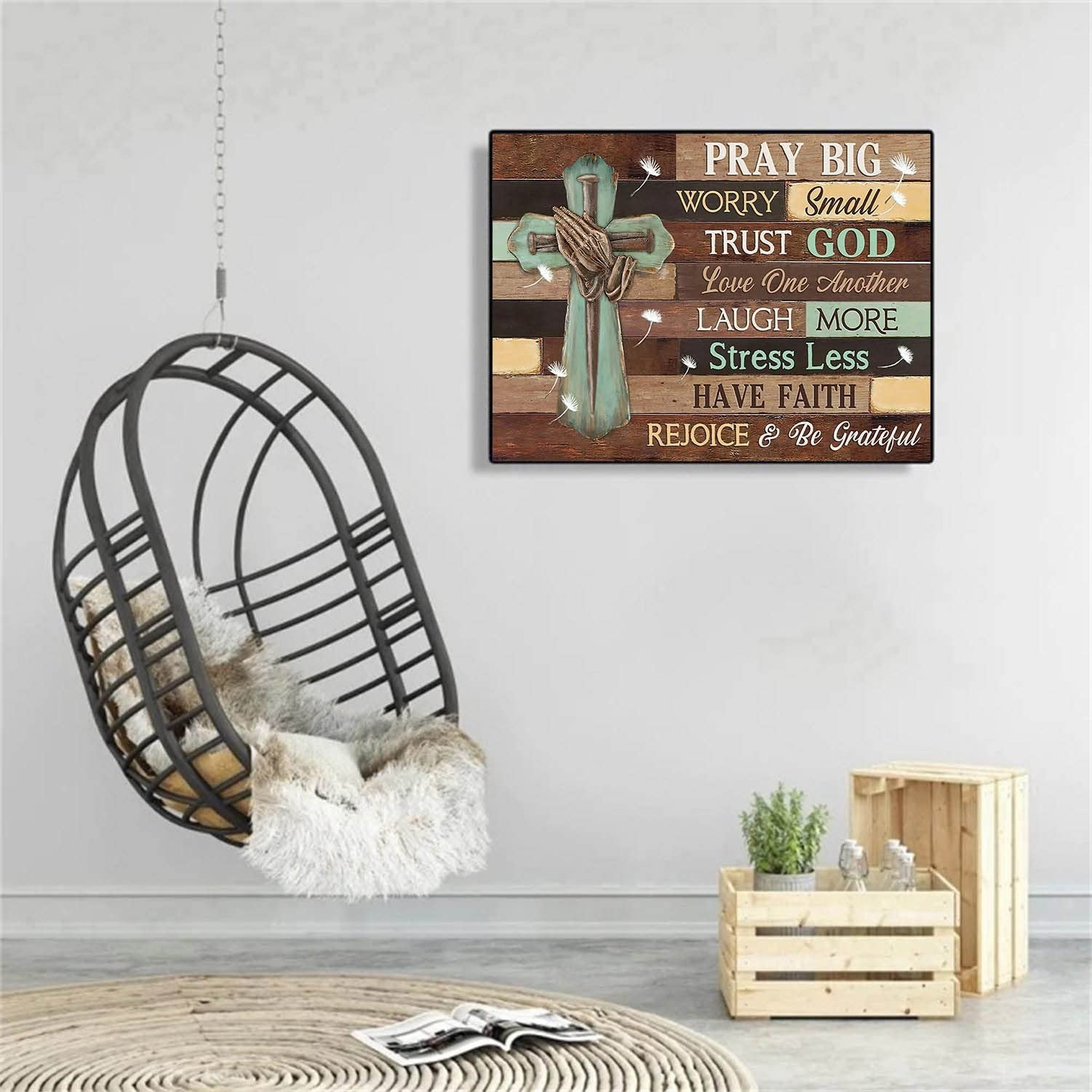 Christian cross with praying hands and inspirational quotes on a wooden plank background, in a room with a hanging chair and wooden crates.