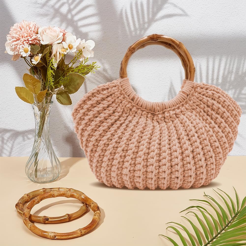 Pink crochet tote bag with bamboo handles, displayed with a vase of flowers and extra handles.