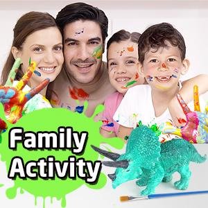 Family smiling with paint on faces, holding painted hands, with dinosaur figurines and paint brushes in foreground.