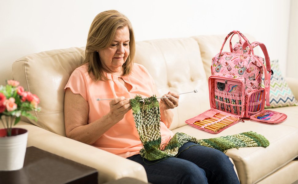 Woman knitting on a couch next to an open pink knitting and crochet backpack filled with supplies.