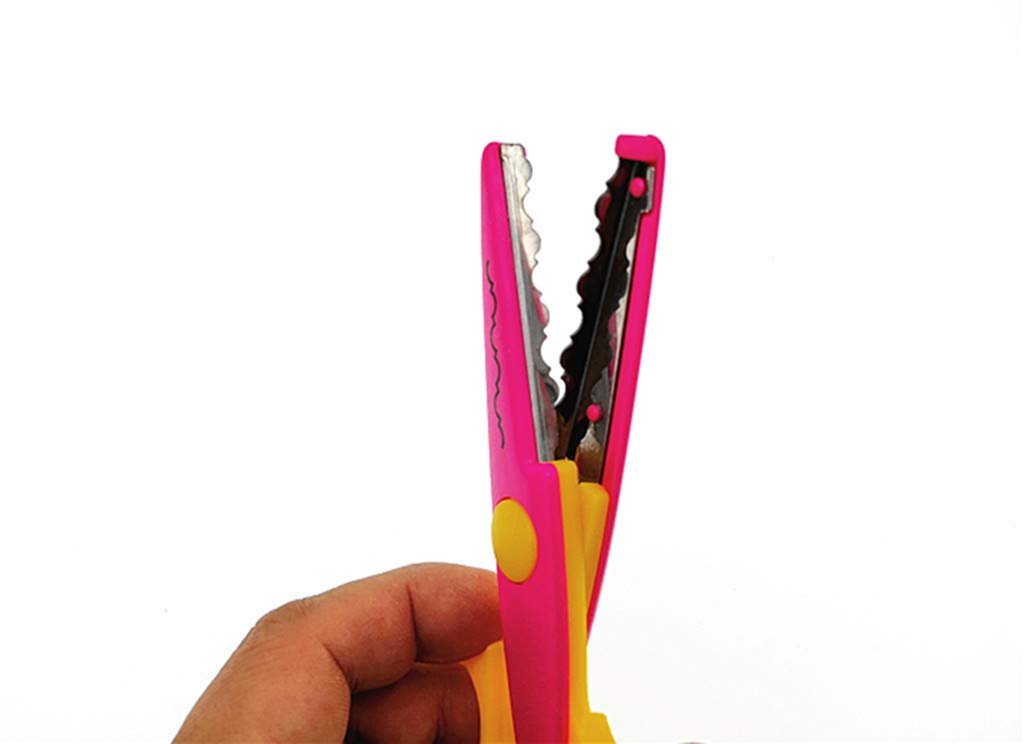 Hand holding pink and yellow wavy paper edger scissors with serrated blades open against a white background.