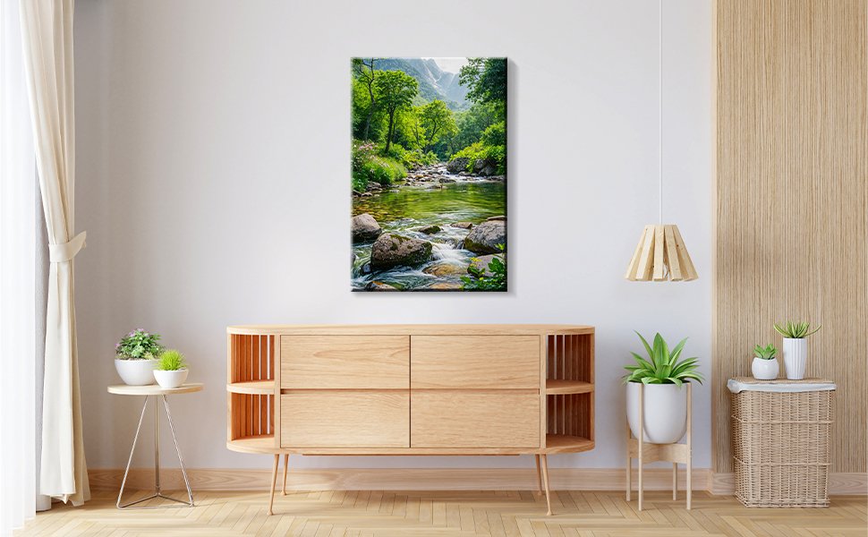Framed landscape painting of a forest stream with rocks and trees, displayed above a wooden credenza.