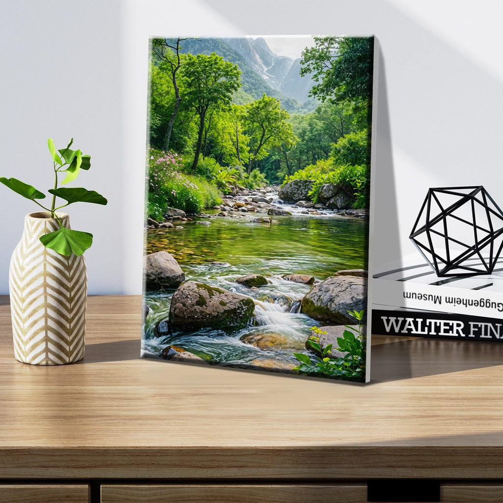 Framed canvas print of a vibrant green forest stream with rocks and mountains in the background.