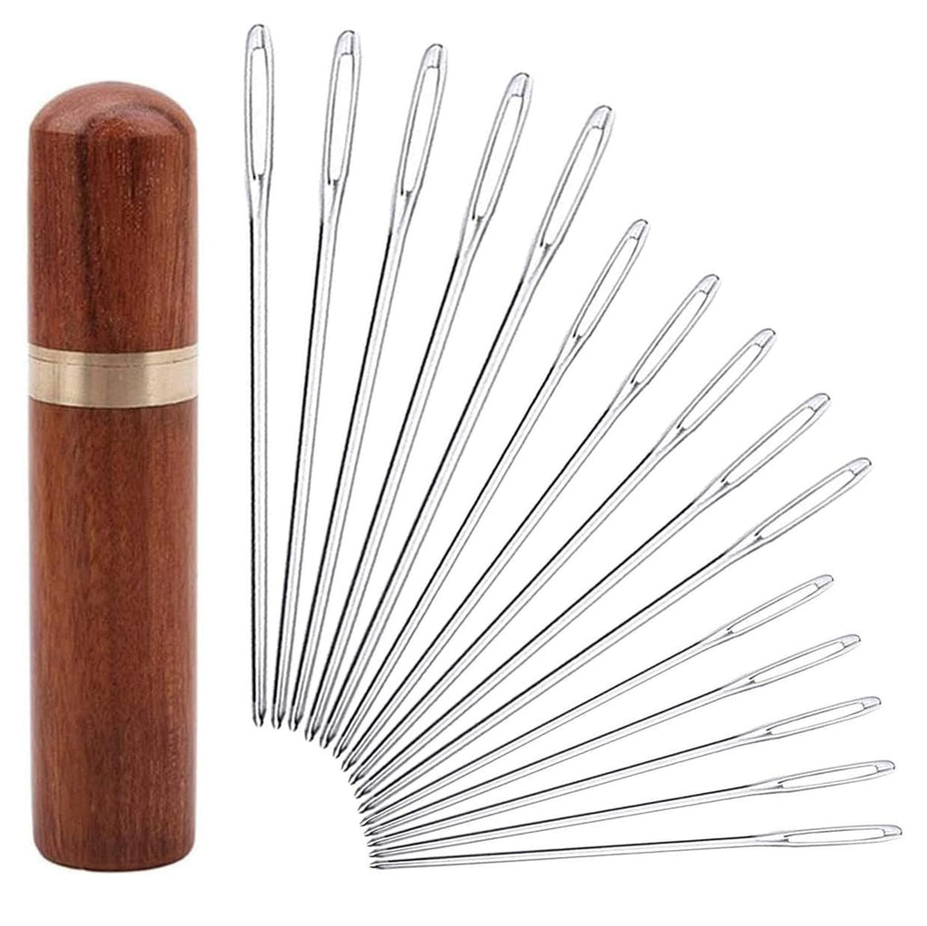 Set of 15 large eye blunt darning needles fanned out next to a wooden storage case with a brass band.