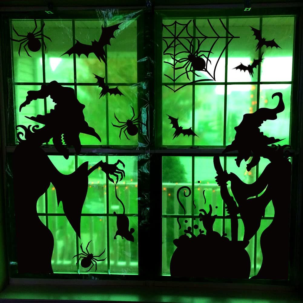Halloween window clings featuring witches, bats, spiders, and a cauldron applied to a green-tinted window.