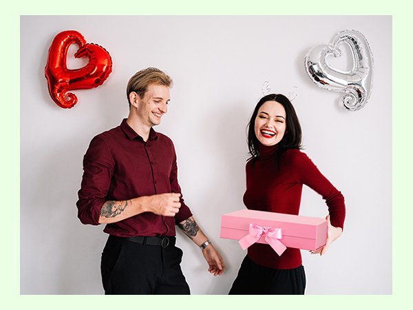Couple celebrating with a pink gift box and heart balloons