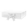 Closed white magnetic gift box with a satin ribbon tied in a bow on the front, shown at an angle on a white background.
