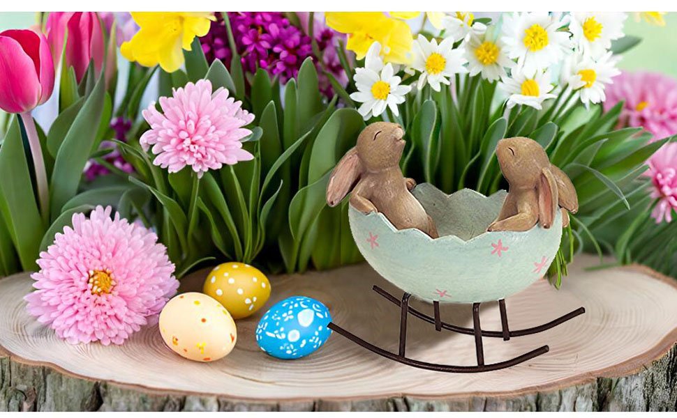 Easter figurine of two bunnies in a rocking egg cradle surrounded by spring flowers and decorated eggs.