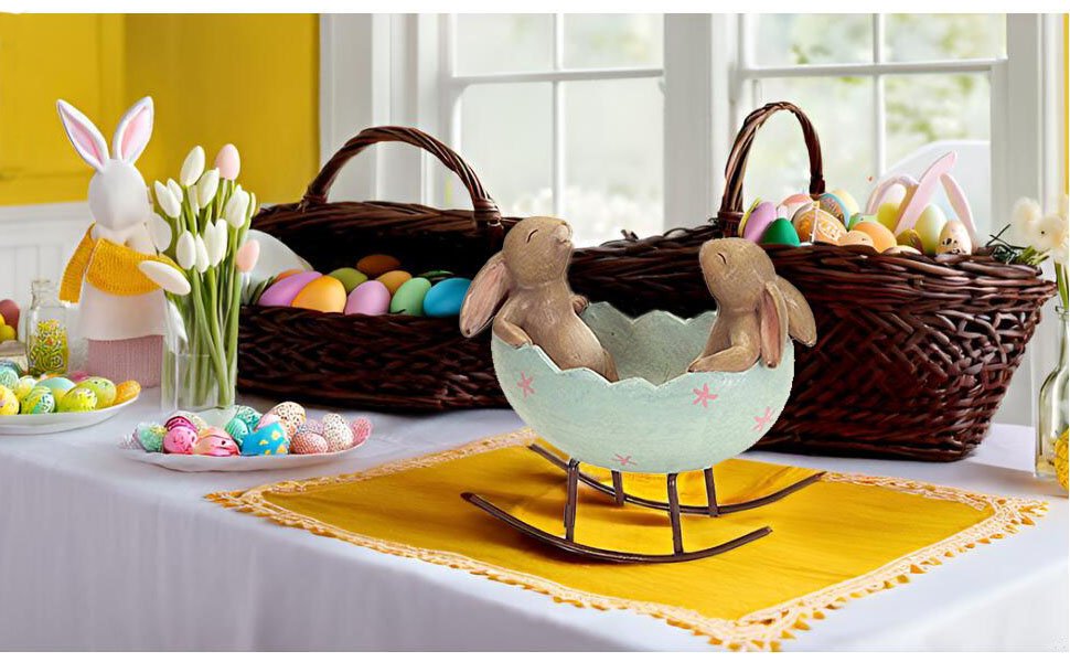 Easter table setting with bunny figurine, tulips, baskets of eggs, and a rocking egg cradle with two bunnies.