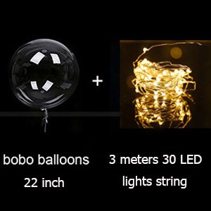 Clear bobo balloon with string tied to it, next to a coil of warm white LED string lights on a dark background.