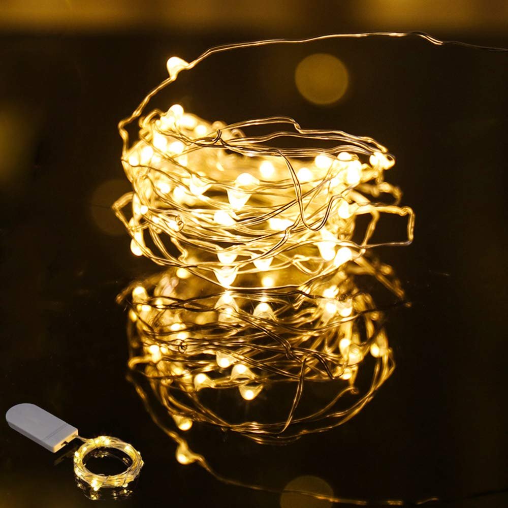 Warm white LED string lights coiled with a battery pack on a reflective surface