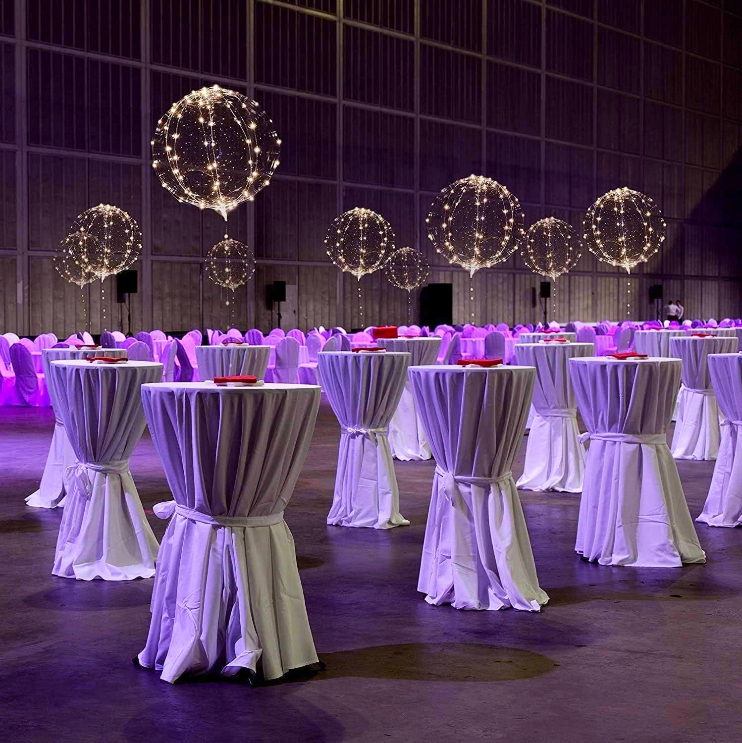 Clear LED light-up balloons floating above draped tables in a large event space