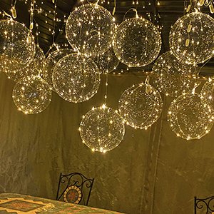 Cluster of 20-inch clear LED light-up bobo balloons hanging indoors above a table.