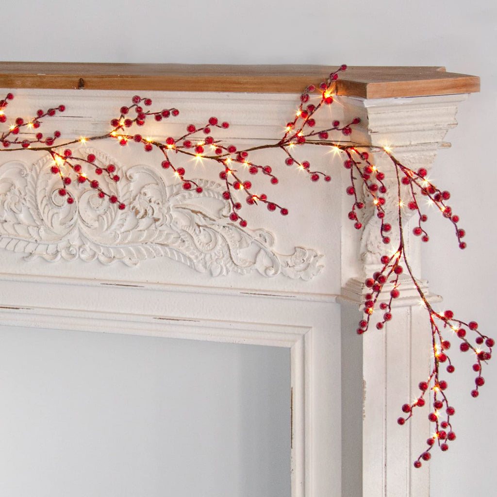 Lighted red berry garland with warm white LED lights draped over a decorative white mantelpiece.