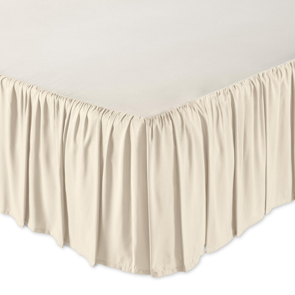Close-up of a beige ruffled bed skirt on a bed, showing the pleats and hem.