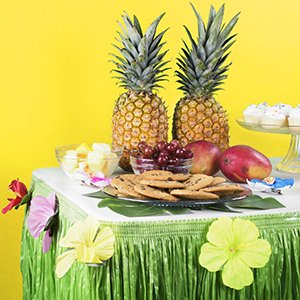 Luau table skirt with silk hibiscus flowers and tropical fruit display on a table