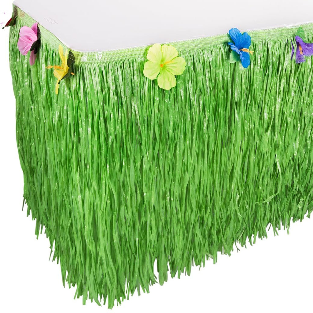Green luau grass table skirt with colorful hibiscus flowers attached to the top edge, draped over a table.