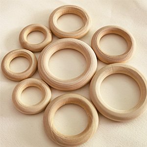 Assortment of natural wood rings in various sizes arranged on a light textured surface.