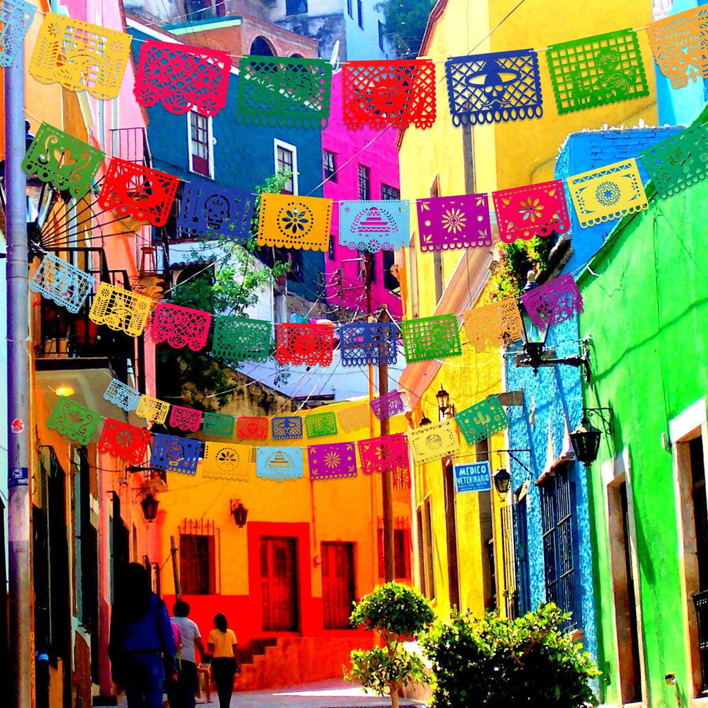 Colorful Mexican Papel Picado banners strung across a vibrant street with people walking.