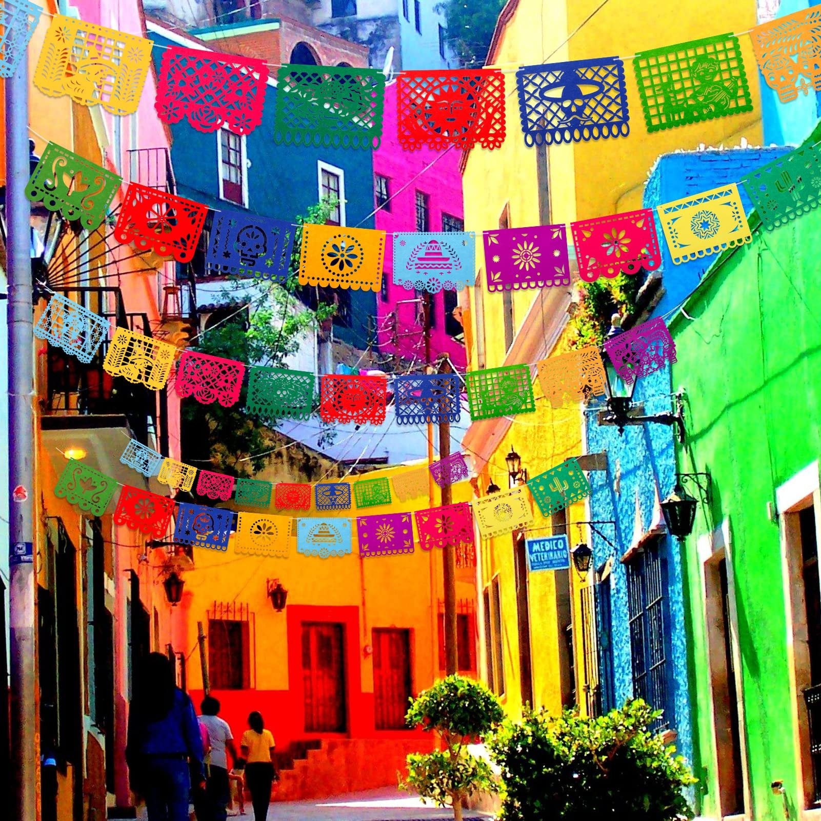 Colorful Mexican Papel Picado banners strung across a vibrant street with people walking.