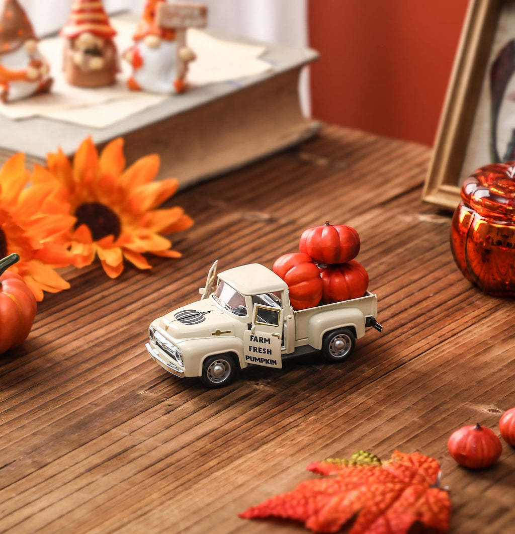 Cream colored metal farm truck with pumpkins in the bed, set on a wooden surface with fall decor.
