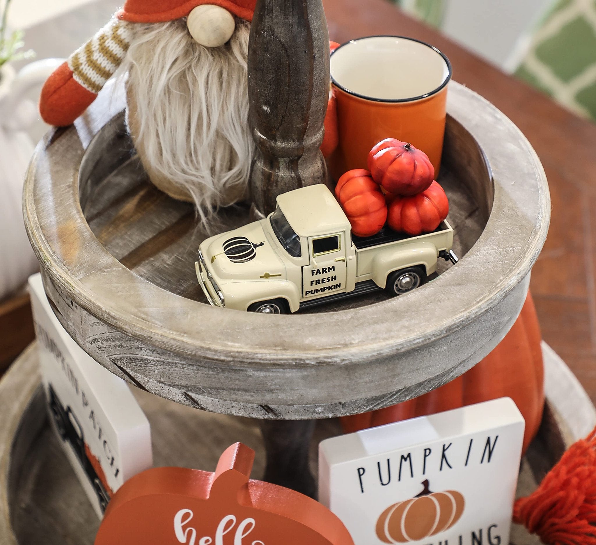 Tiered tray fall decor with a cream metal farm truck carrying pumpkins, a gnome, and an orange mug.