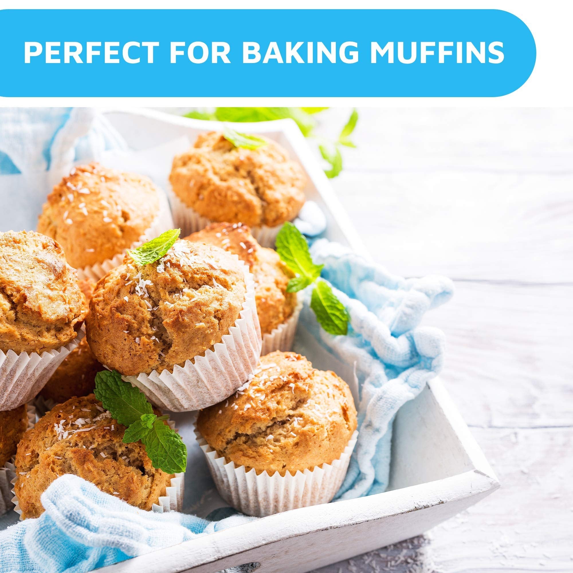 Mini white cupcake liners filled with muffins topped with coconut and mint leaves in a wooden tray