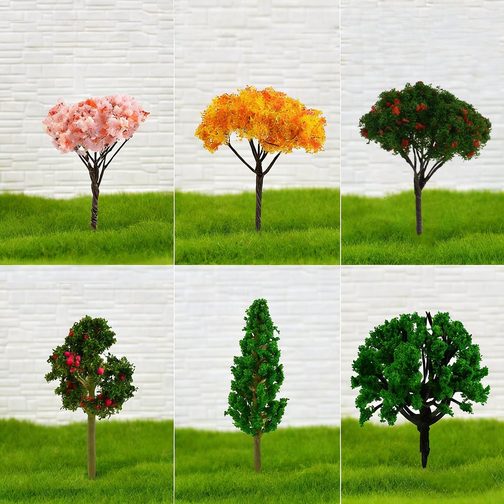 Six miniature artificial trees with different foliage colors and shapes, set against a white brick background and green grass.