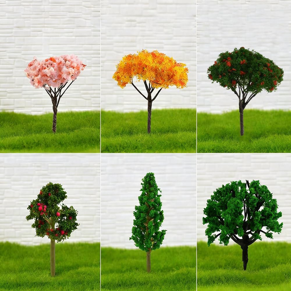 Six miniature artificial trees with pink, orange, and green foliage on grassy bases against a white brick wall.
