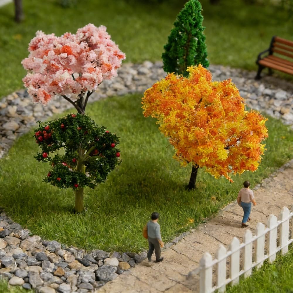 Miniature garden scene with four artificial trees, two small figures walking on a path, and a white picket fence.