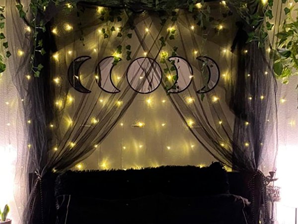 Five moon phase acrylic mirrors arranged on a wall decorated with black tulle and fairy lights.