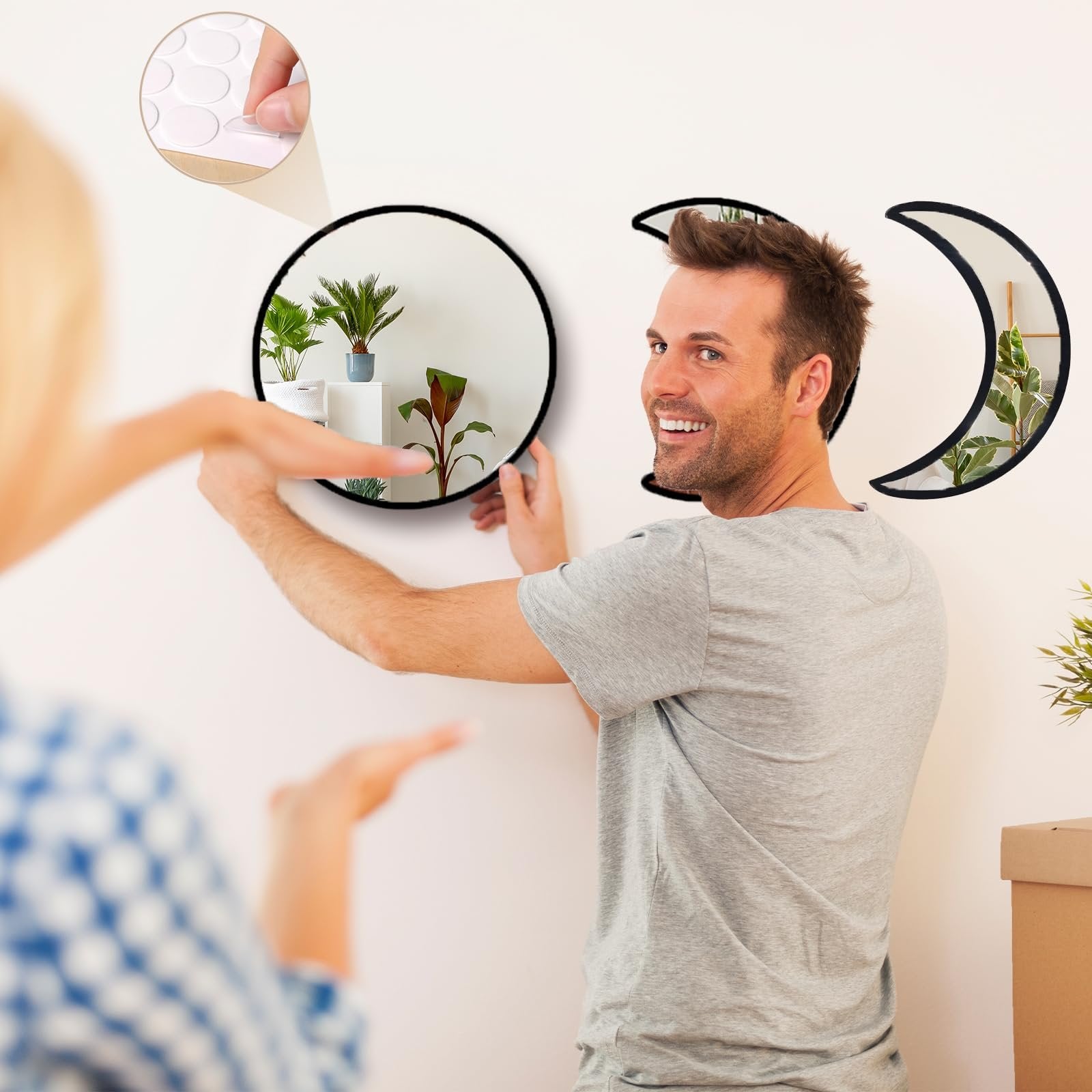 Man and woman hanging moon phase acrylic mirrors on wall, showing installation with adhesive dots