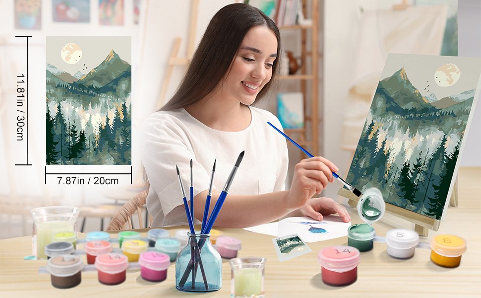 Woman painting a mountain landscape on canvas with acrylic paints and brushes, kit contents visible