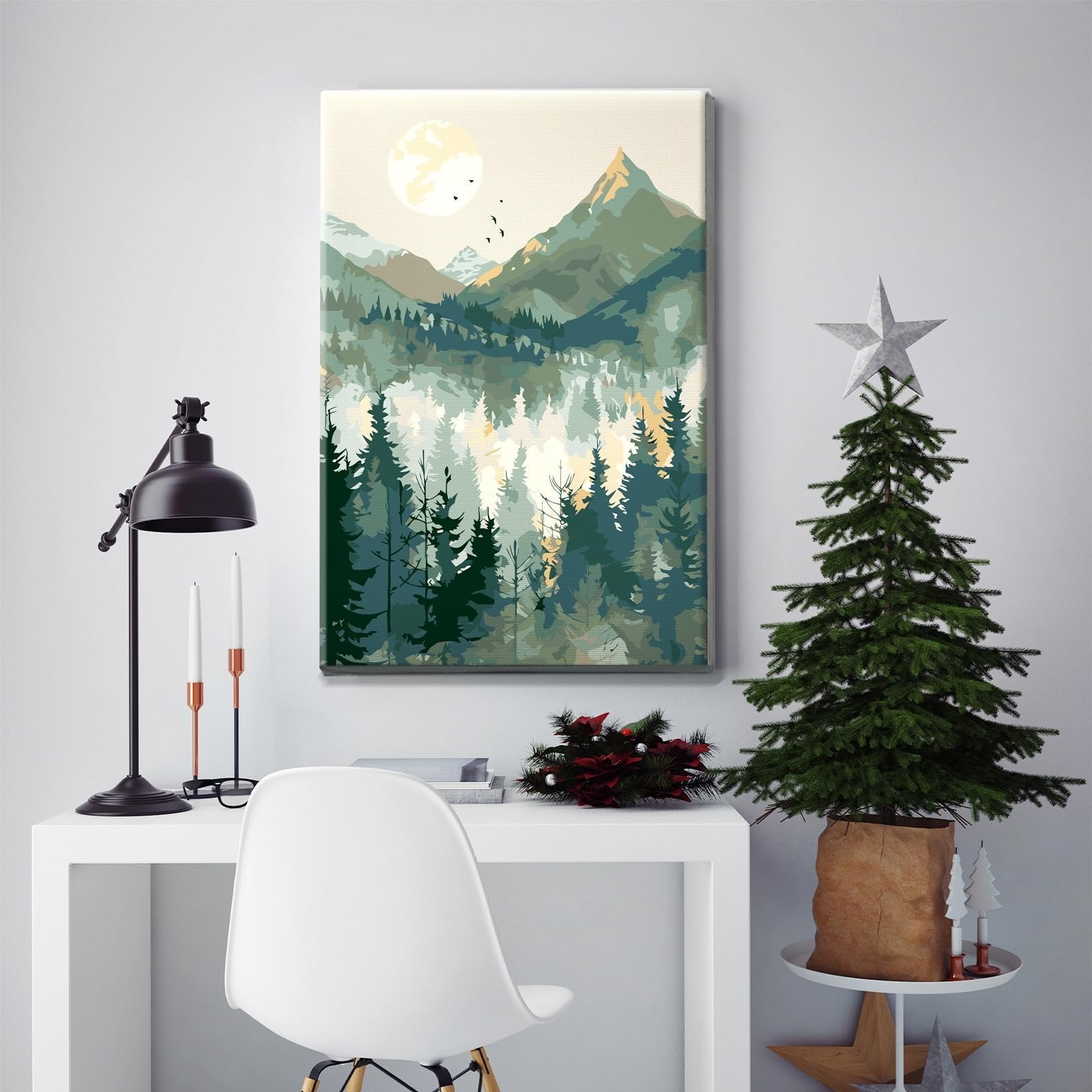 Paint by number canvas depicting a mountain landscape with a forest and moon, displayed on a desk with a lamp and Christmas tree.