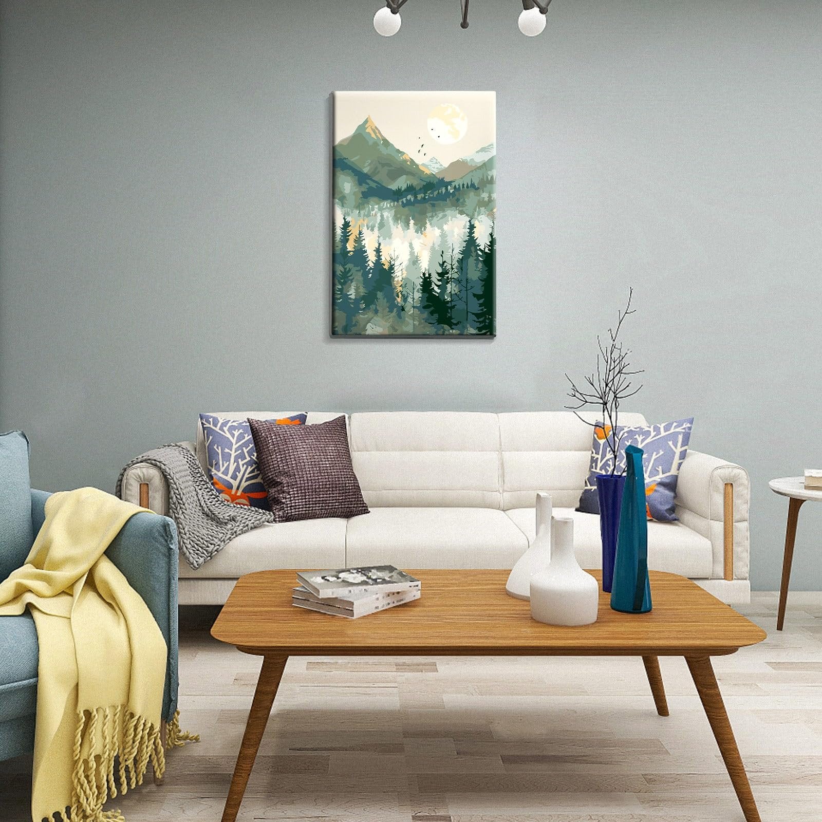Framed mountain landscape paint by number artwork hanging on a wall above a sofa