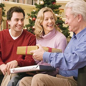 Family exchanging Christmas gifts in front of a decorated tree, smiling and laughing.