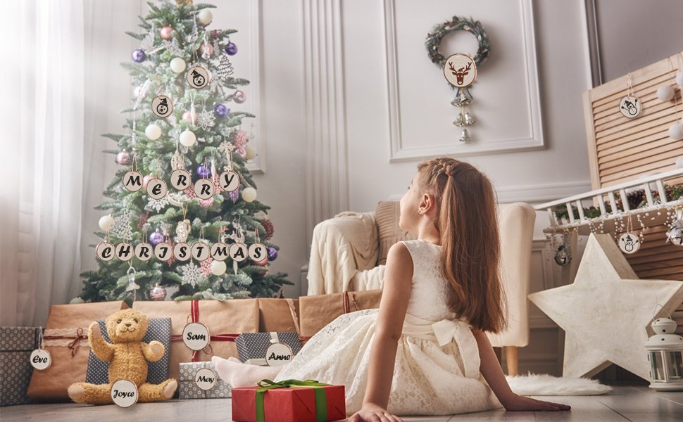 Girl in white dress looking at Christmas tree with wooden ornaments and gifts below