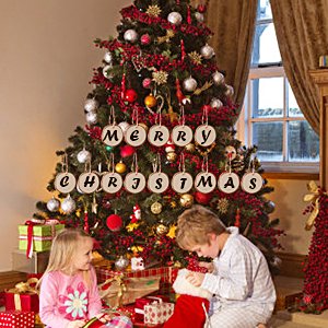 Children opening presents near a decorated Christmas tree with wooden slice ornaments spelling 'Merry Christmas'