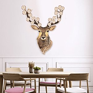 Deer head wall decor with ornate antlers, mounted on a white wall above a dining table.