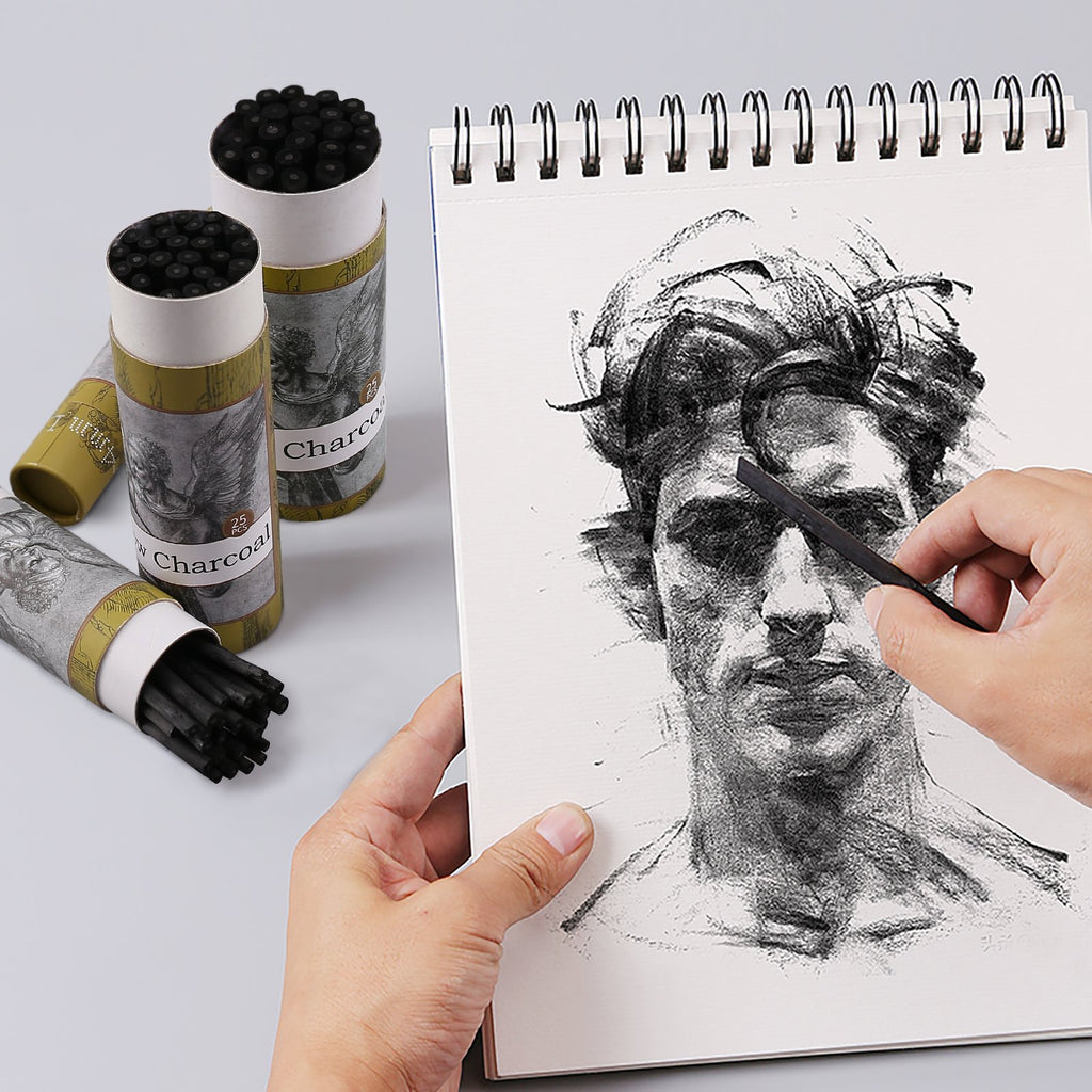 Artist's hands sketching a portrait with charcoal sticks and a sketchbook