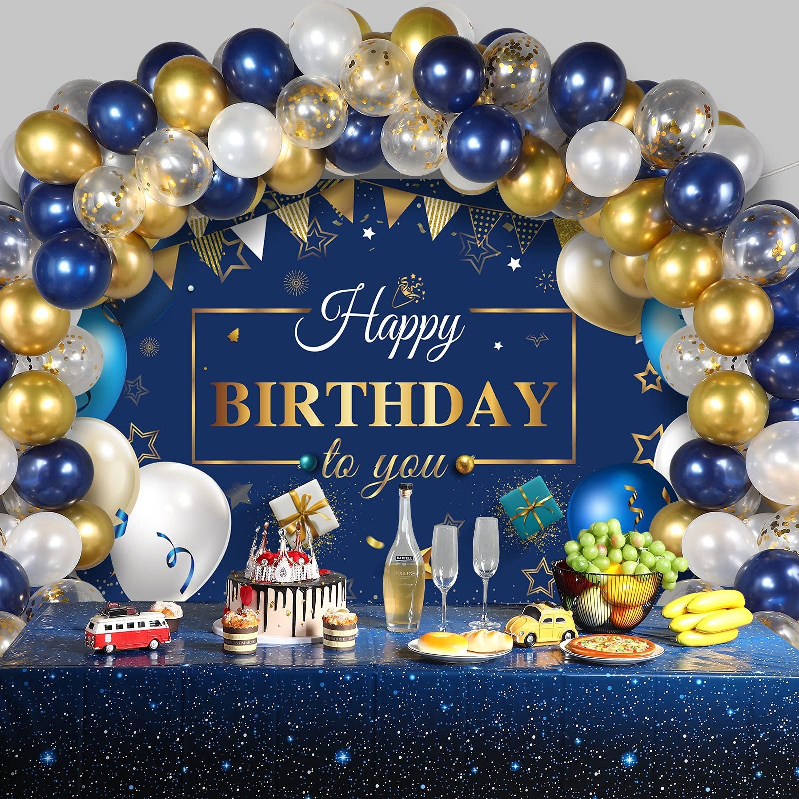 Navy blue and gold birthday party scene with balloons, cake, champagne, and food on a starry tablecloth.