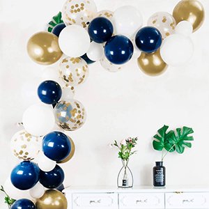 Navy blue, pearl white, and gold confetti balloons arranged in an arch over a white dresser with decorative plants.