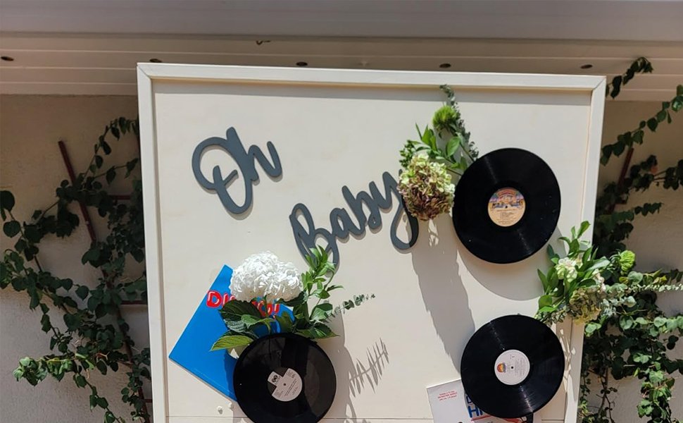 Wooden 'Oh Baby' sign with vinyl records and flowers for a baby shower backdrop
