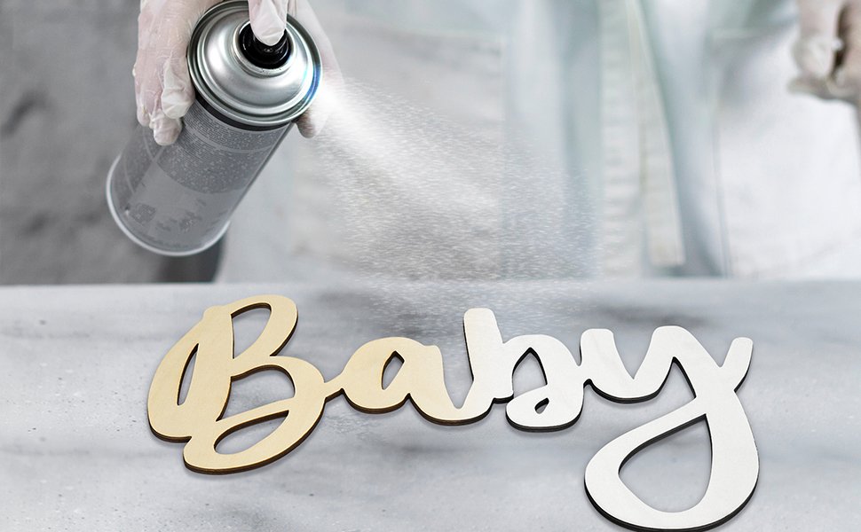 Wooden 'Baby' sign being sprayed with white paint from a can, close-up shot