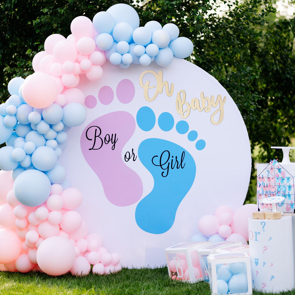 Gender reveal party backdrop with pink and blue balloons, a white circle with footprints, and text 'Oh Baby Boy or Girl'.