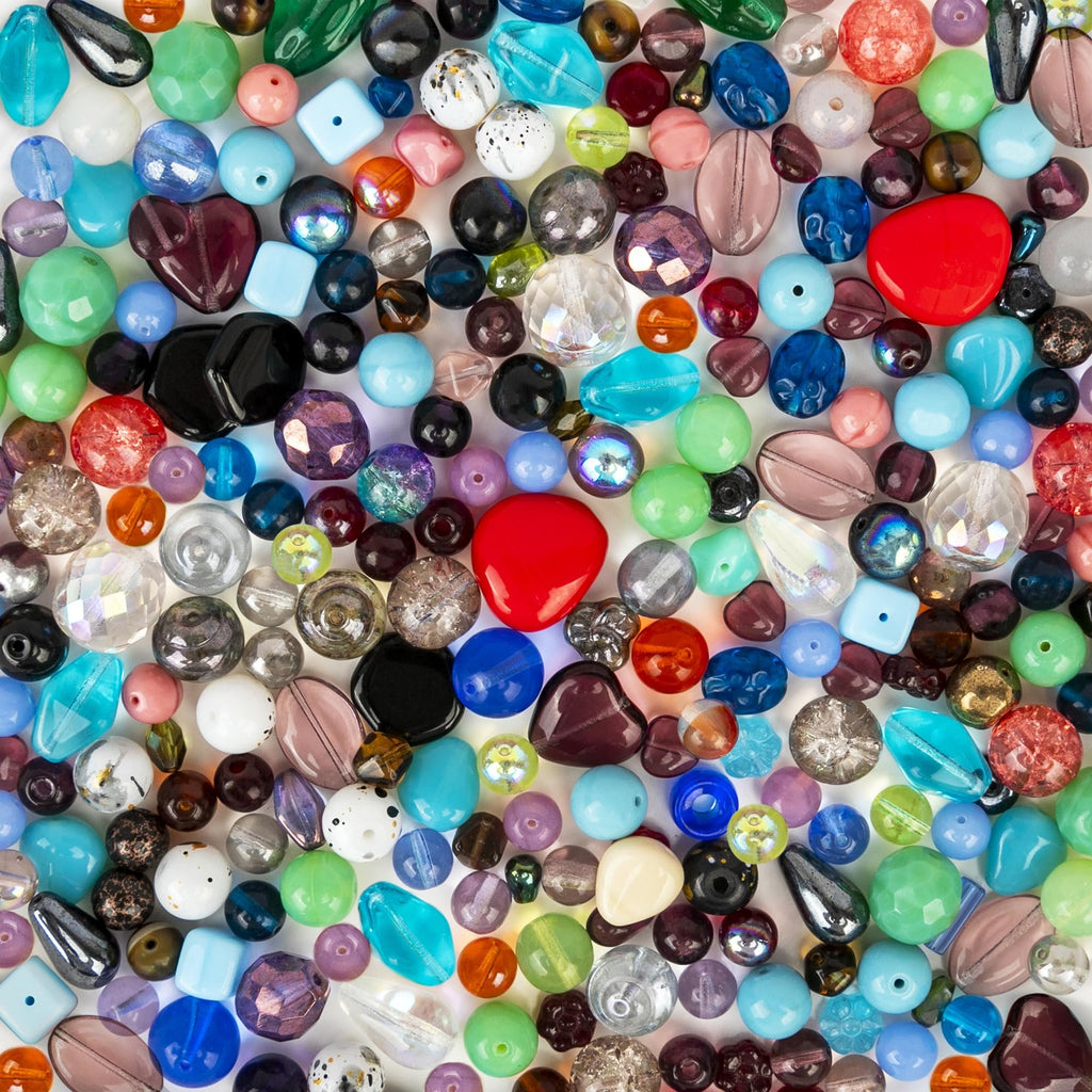 Assorted glass beads in various shapes, sizes, and colors, including red hearts, teardrops, and round beads, for jewelry making.